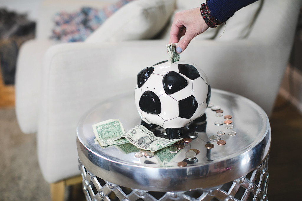 Putting money into piggy jar bank